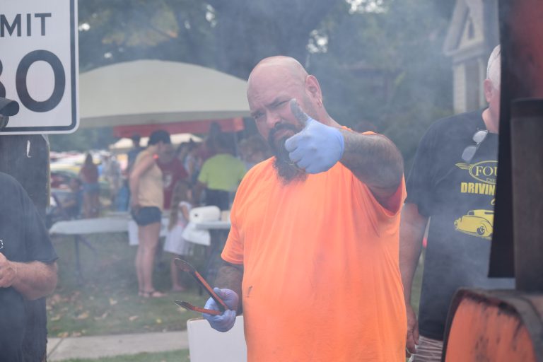 Food vendor in an orange shirt serving guests at the annual La Porte Sunflower Fair