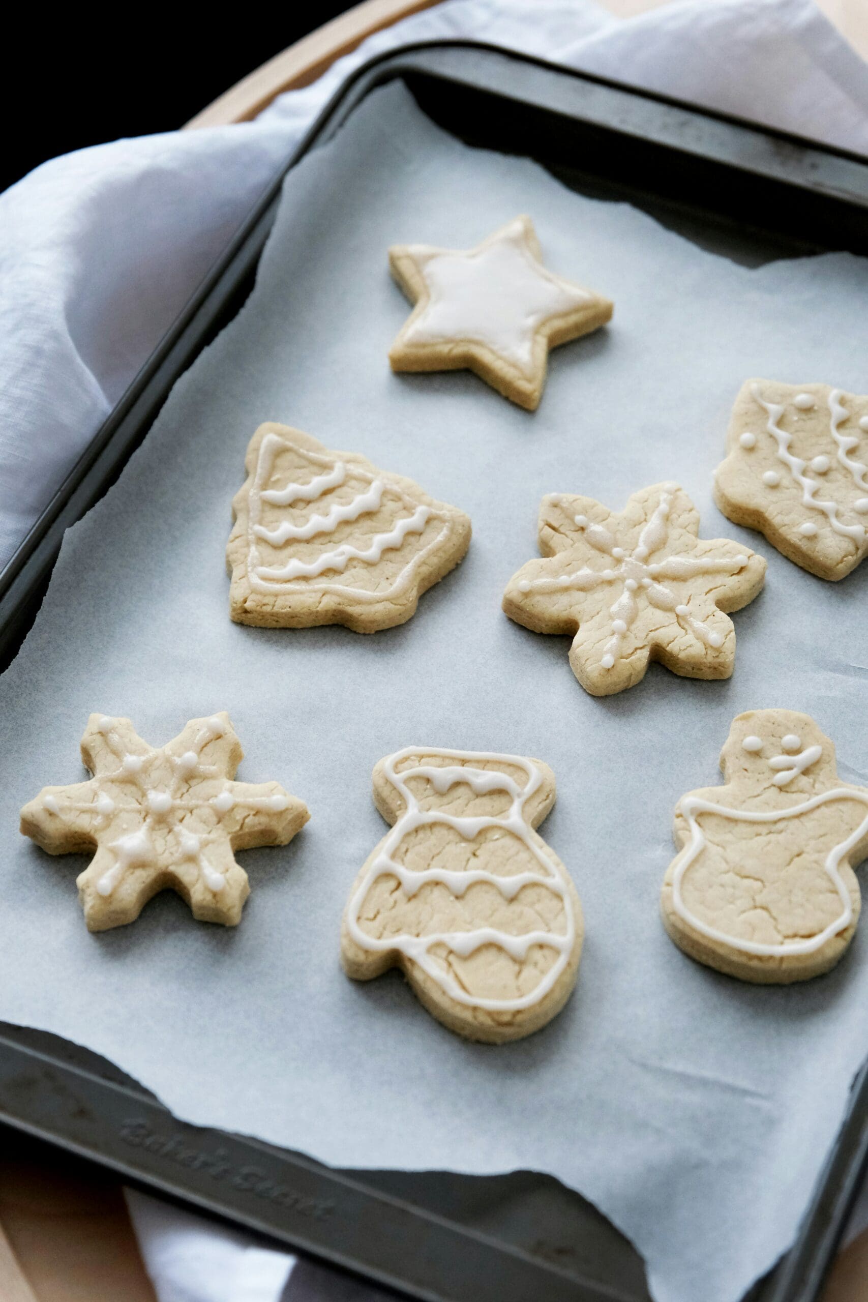 Tree, star, and snowflake holiday sugar cookies on a baking sheet
