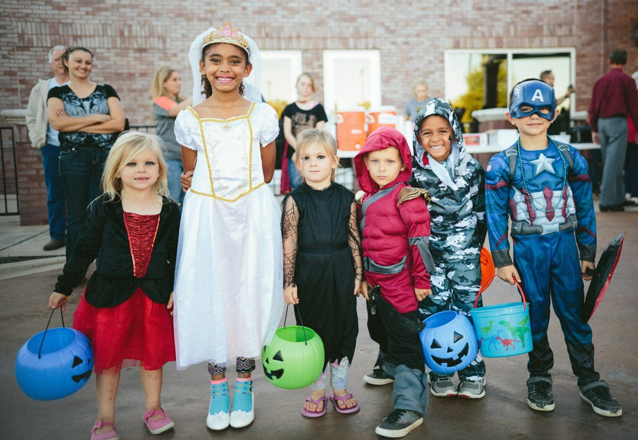 Group of children in Halloween costumes, including a princess and superheroes