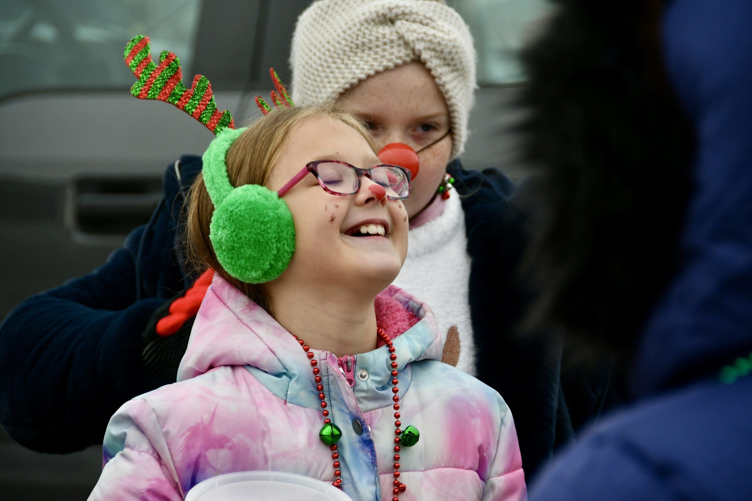 Girl in green earmuffs and a red clown nose smiling at the La Porte Santa Parade downtown