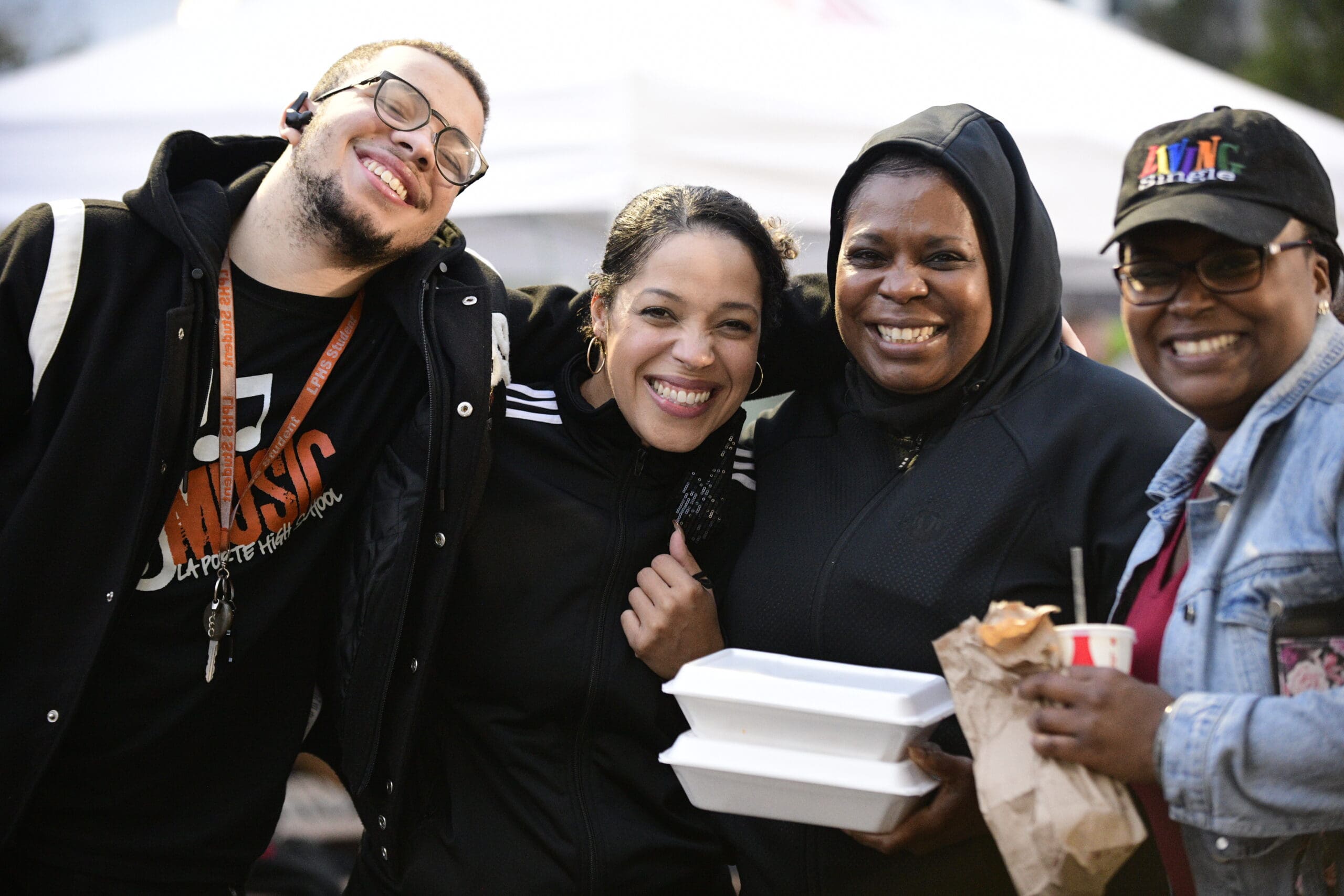 Three friends smiling together at La Porte Taco Fest in downtown La Porte