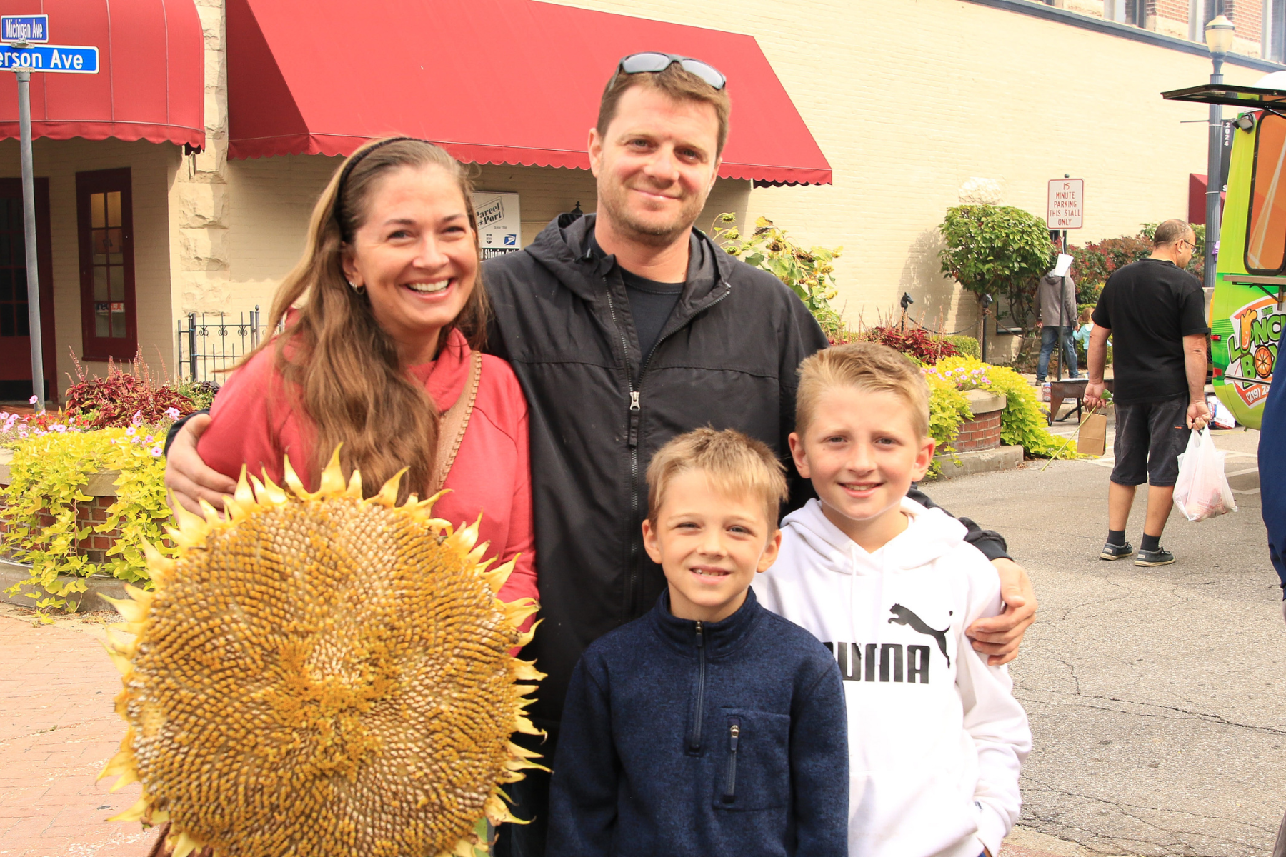 Smiling family of four with sunflowers at the Sunflower Fair in downtown La Porte