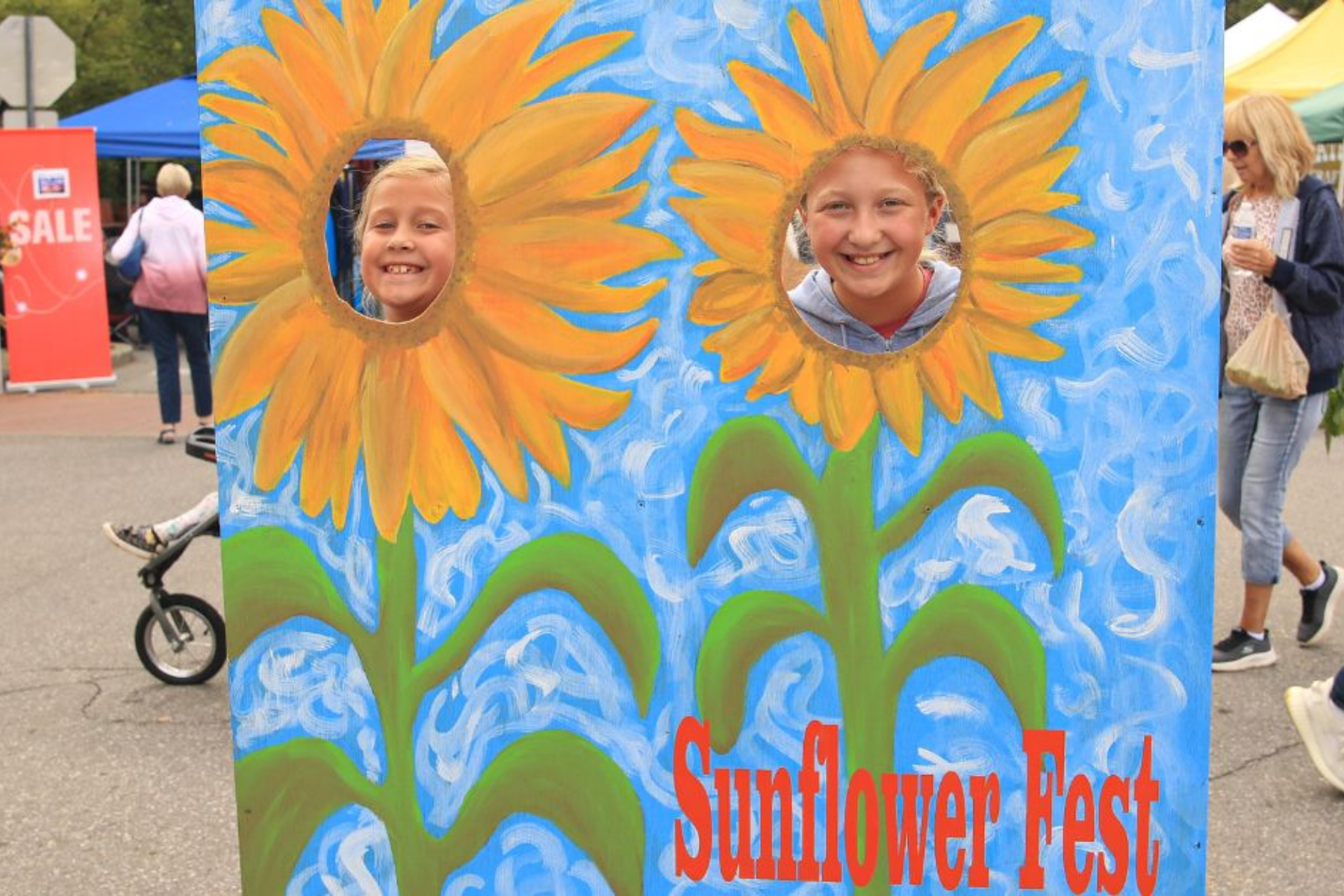 Two children pose in a painted sunflower photo board at the Sunflower Fair in downtown La Porte, Indiana